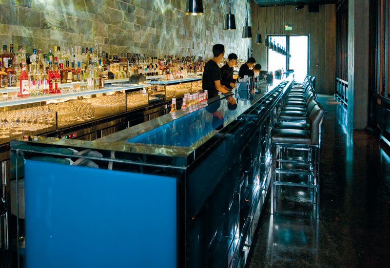NIGHT MODE: The blue glass rectangular bar features a retro-lighted top. The cleaved slate on the back wall with rippled lighting gives a night-time m NIGHT MODE: The blue glass rectangular bar features a retro-lighted top. The cleaved slate on the back wall with rippled lighting gives a night-time m