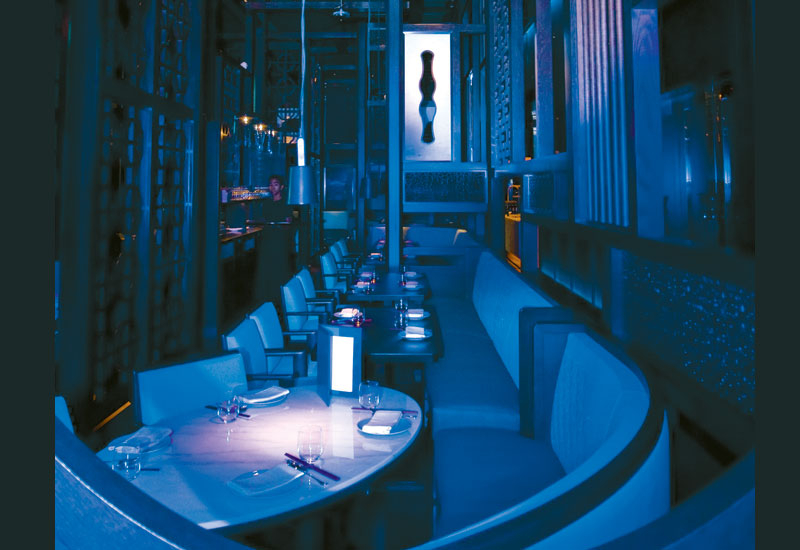 THE CAGE: The main dining wood work structure is surrounded by blue glass retro lighted in a brushed stainless steel frame. THE CAGE: The main dining wood work structure is surrounded by blue glass retro lighted in a brushed stainless steel frame.